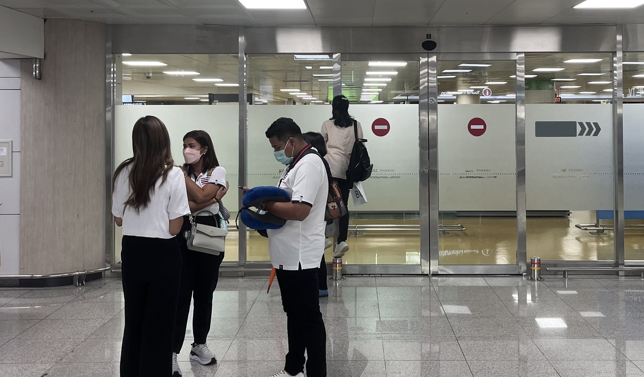      제주국제공항 입국장에서 대기중인 태국인 관광객 가이드들 한 태국인 가이드가 입국장 안을 들여다보고 있다 .